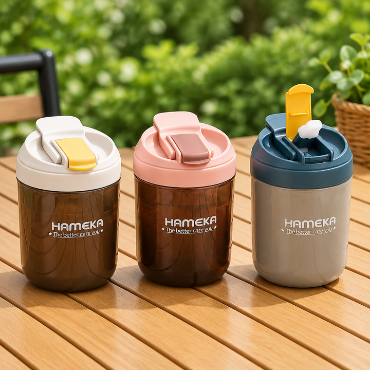 Three colorful tumblers with lids on a wooden surface outdoors